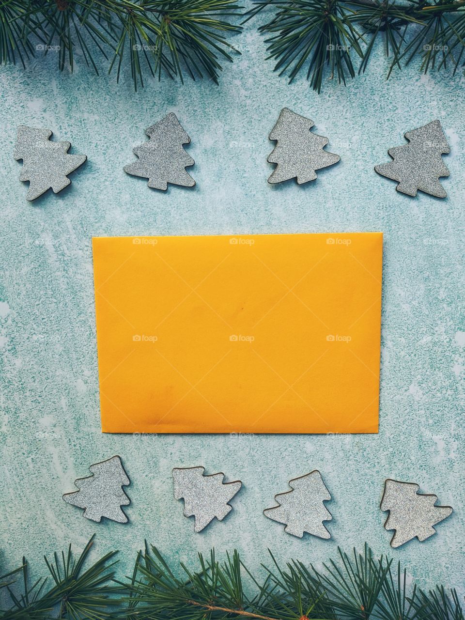 Christmas or New Year composition.  Paper yellow envelope with fir branches on a blue background. Flat lay. Top view.