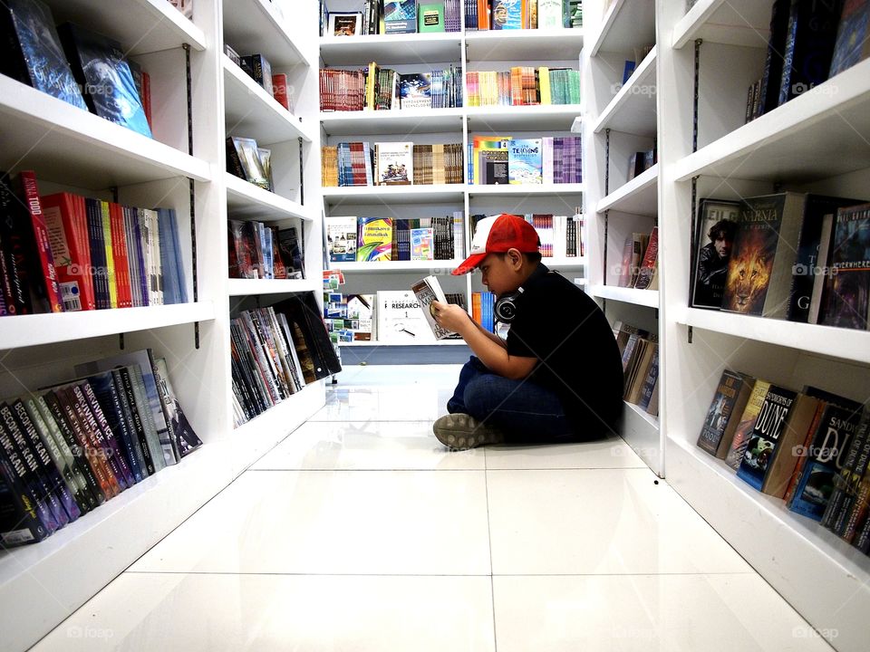 a boy reading a book inside a bookstore