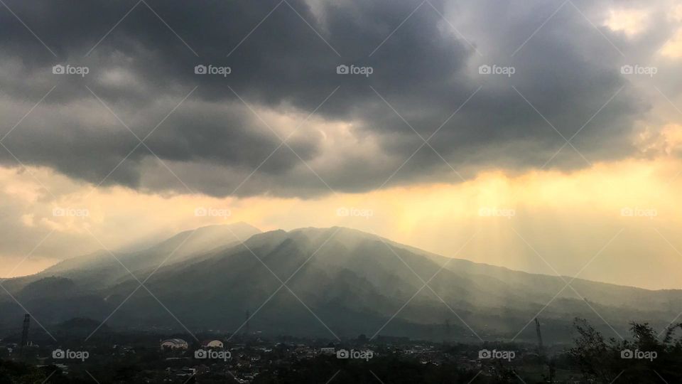 The sun that hides its beauty behind the clouds and mountains. Afternoon. Late afternoon. Sky. Cloud. Cloudy. Mountain. Ray. Light. Sunlight. Sun. Scenes. Photography. Scenery. Landscapes. Tranquil.