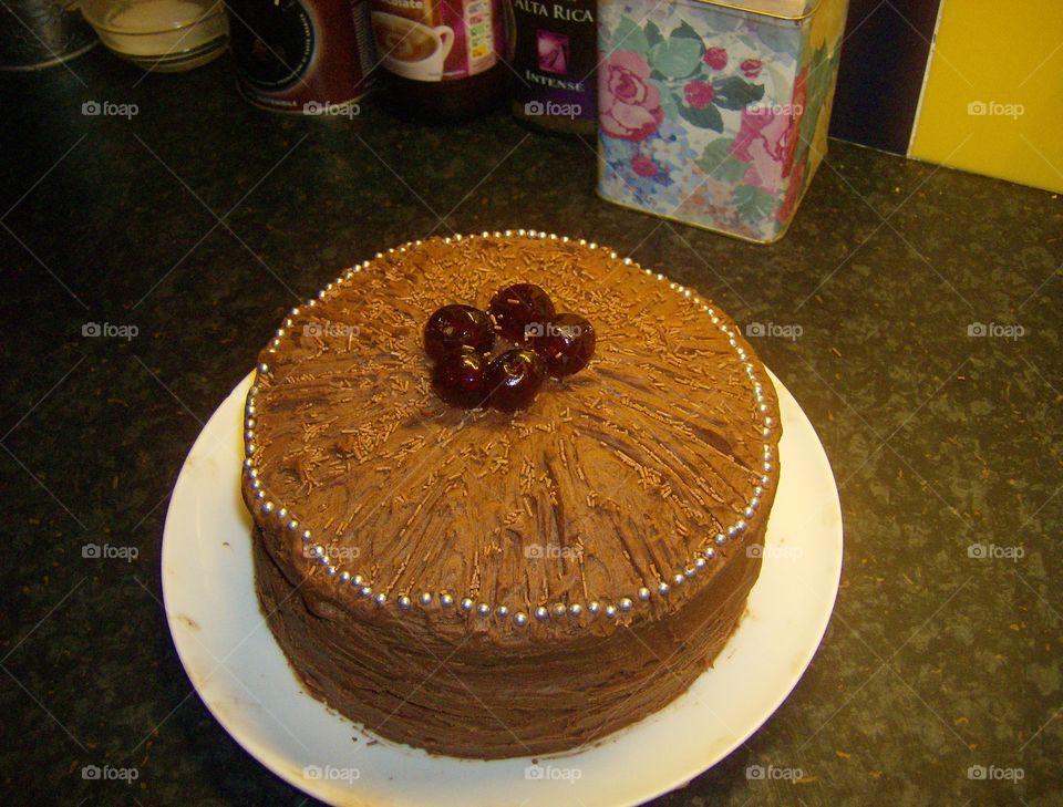 large homemade chocolate cake with glace cherry decoration on top and silver balls retro baking large sponge indulgent