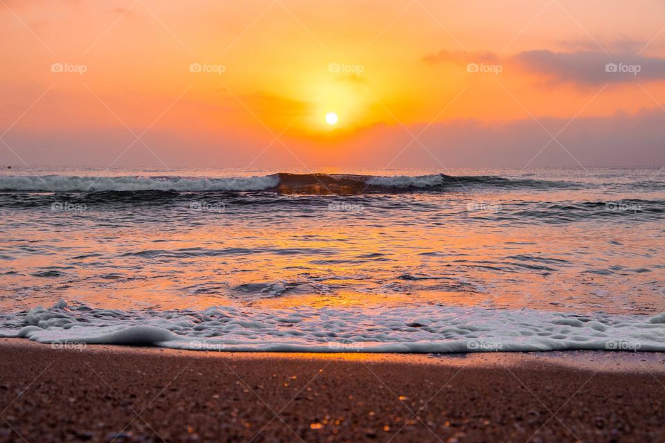 Sunrise Over Wavy Ocean On Sandy Beach