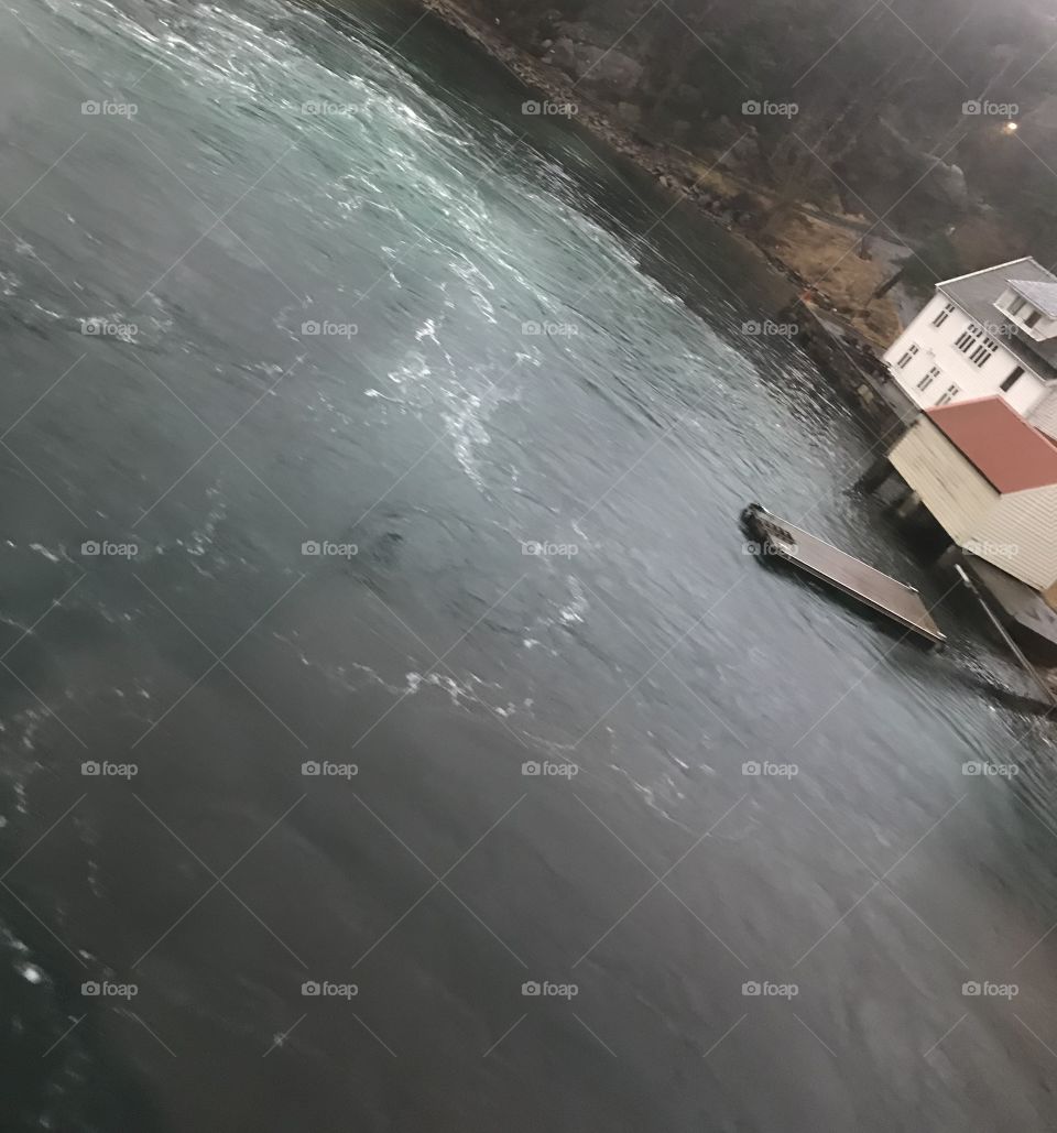 A passenger ferry is leaving port, and is making some small waves in the water. Taken in Norway.