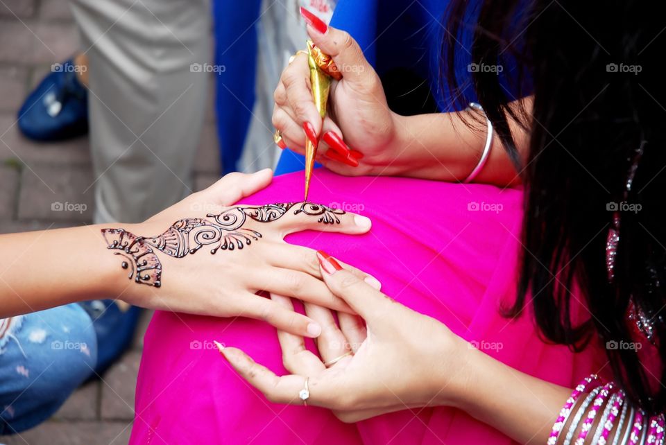 Indian artist draws a temporary henna pattern on the girl's hand