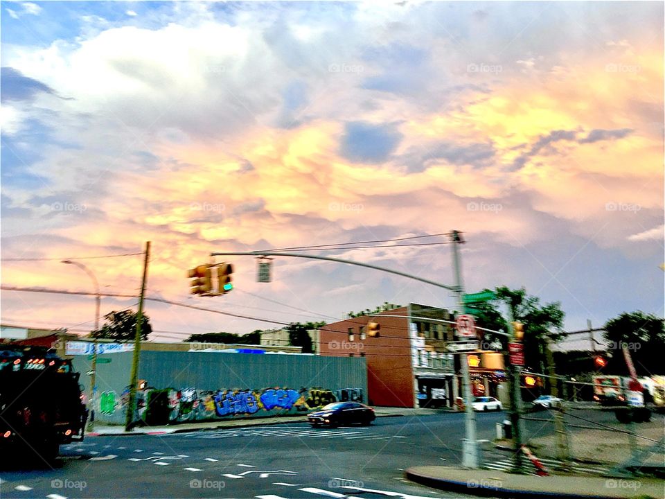 An intersection with traffic lights somewhere in LIC, Queens, NY just around sunset time at the hour of dusk before nightfall: the golden rays of the setting sun color everything from underneath. 2021. Hypnotic Productions