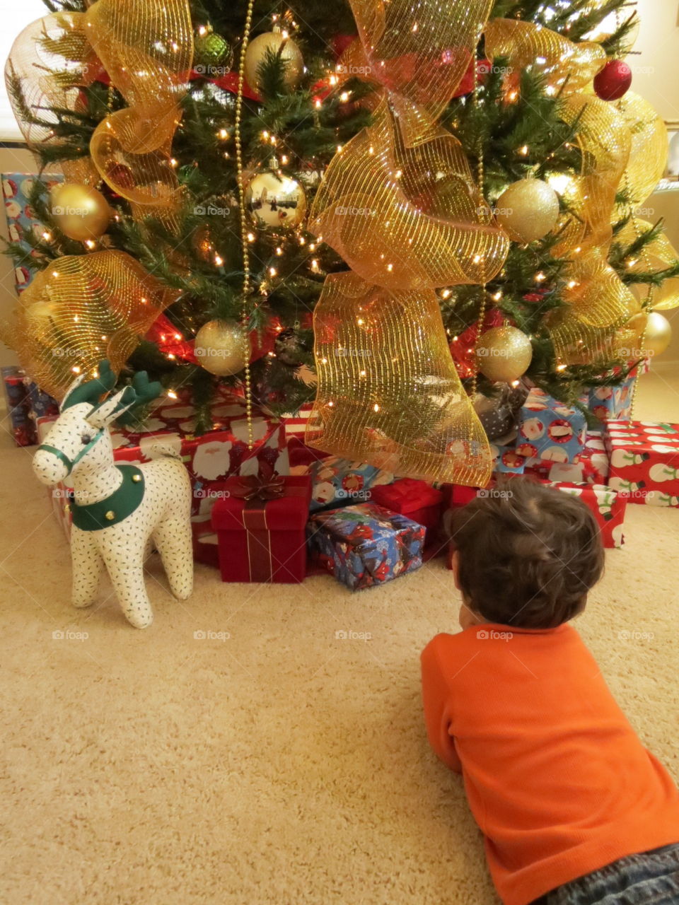 Little boy laying on floor in front of Christmas tree.