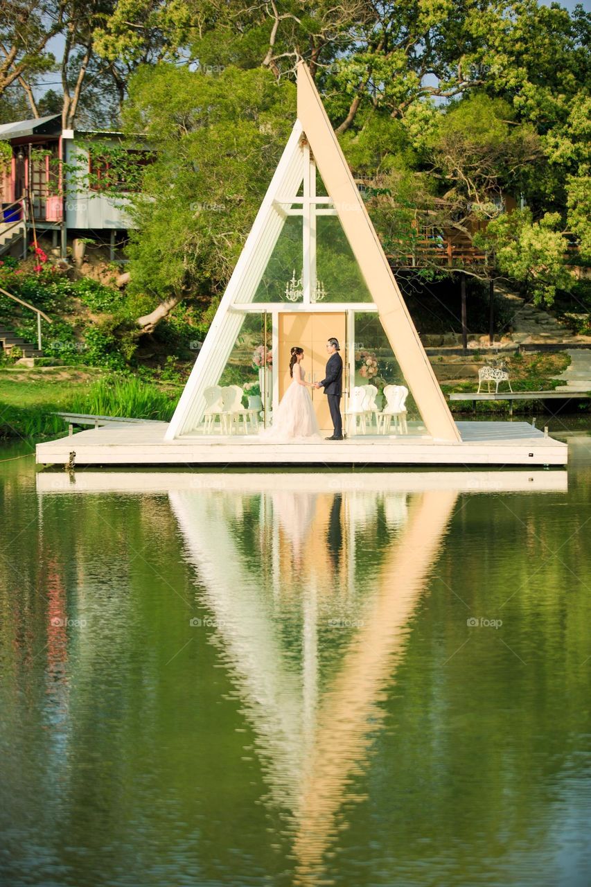 Reflection of love: Bride and Groom in front of a Triangular Church 