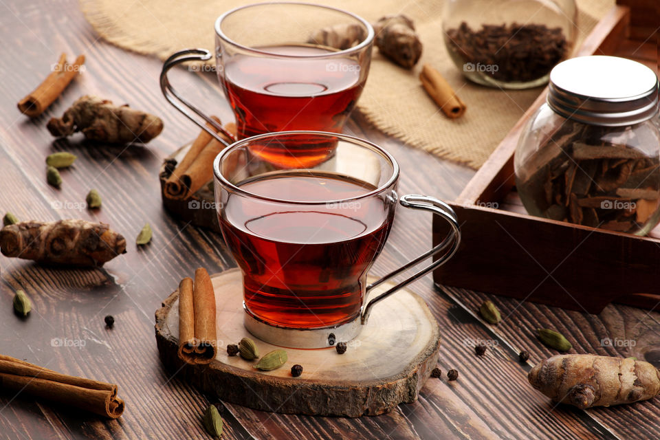 Hot tea cups with ingredients cinnamon, cardamom, black pepper and turmeric