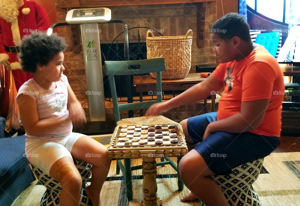 Siblings playing checkers together.