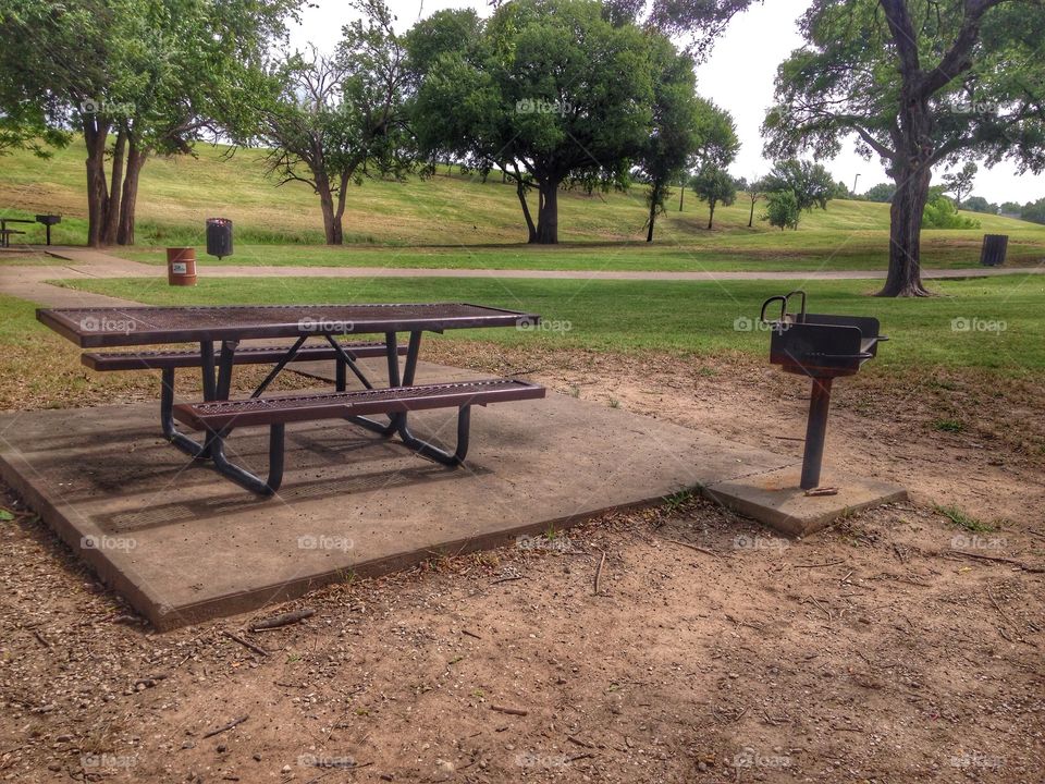 Summer at the park. Picnic table and grill at a park