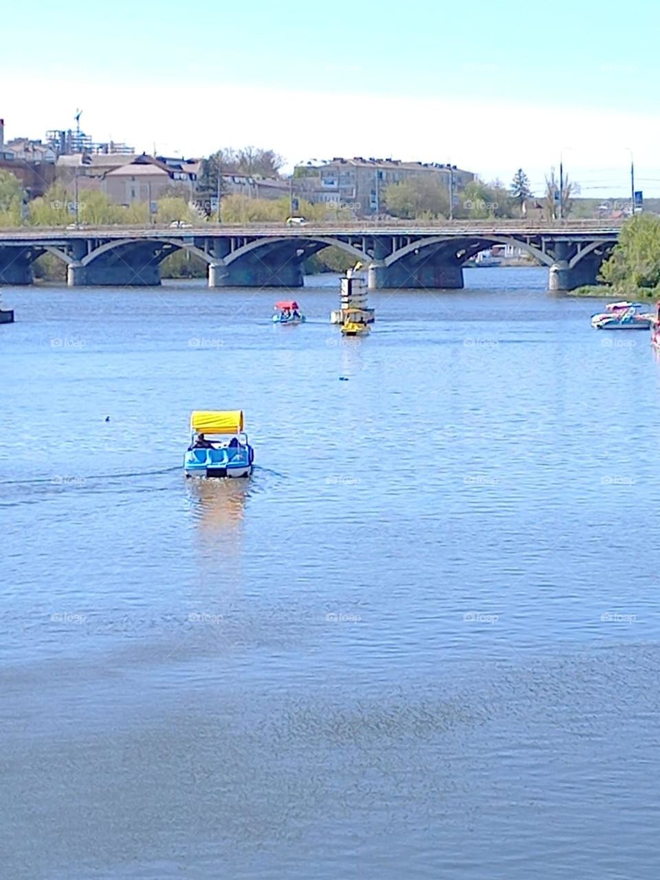 people ride catamarans on the river on a sunny day