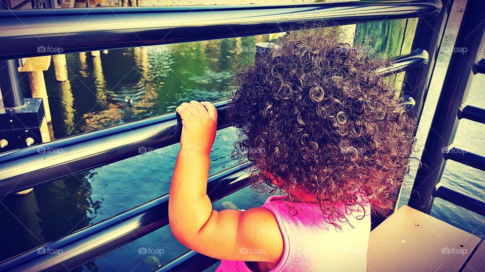 Curly hair small girl standing near railing