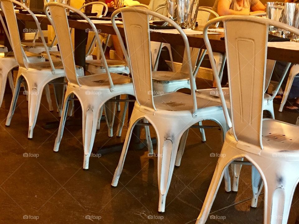 Empty metal chairs at a long table in a restaurant 