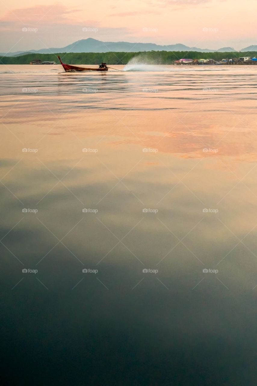 Beautiful Sunrise moment above silhouette of boat in sea
