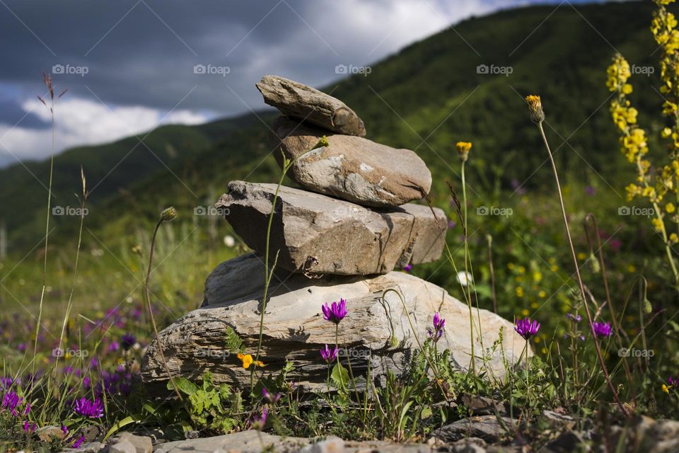 Stone stack with balanced stones on blurred mountain background.