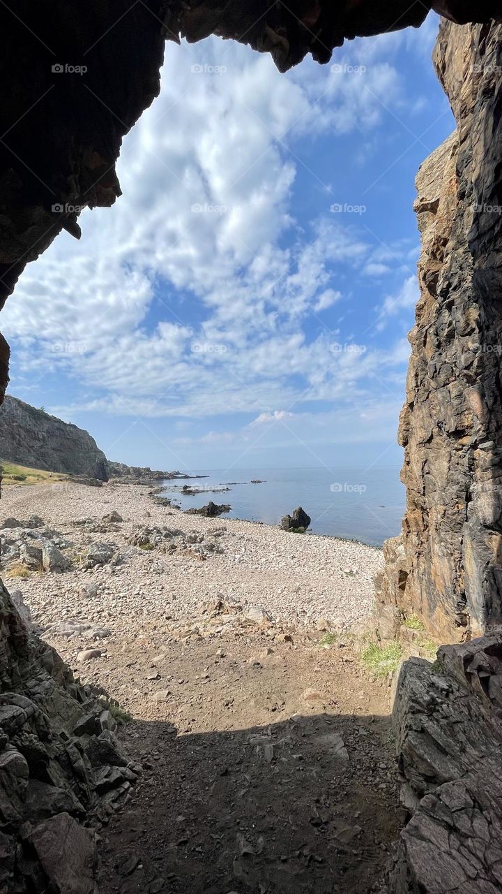 Looking out from a cave , view of pebble beach, ocean and rocks at Hovs Hallar Sweden on a beautiful day