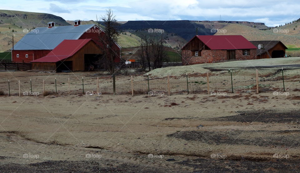A rural country farm against the hills of Eastern Oregon on a spring day. 