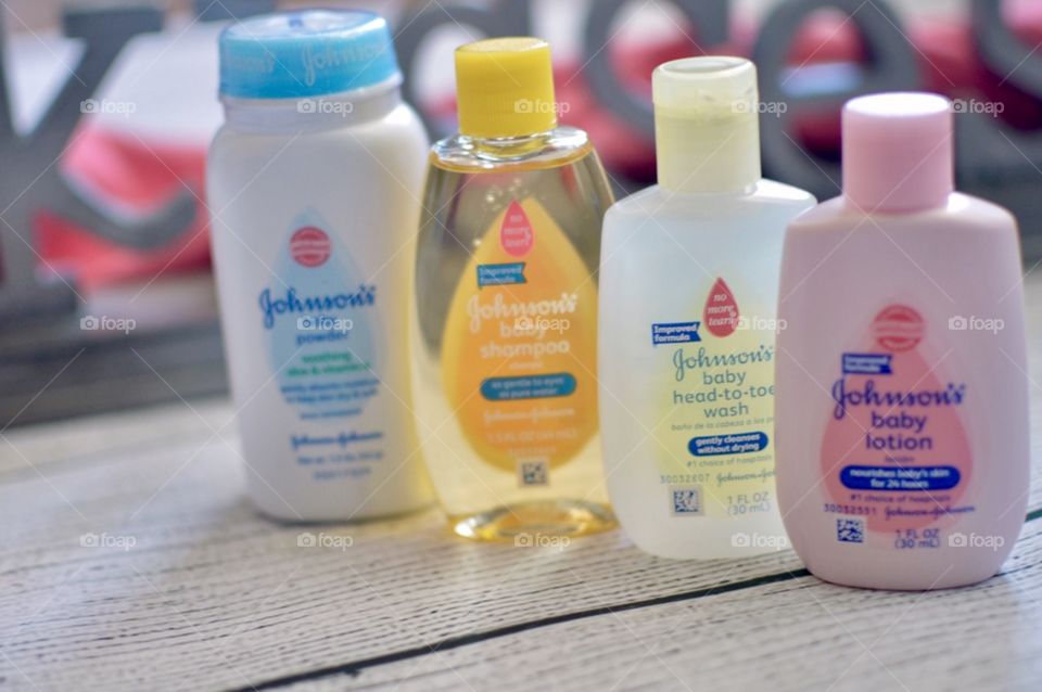 Johnson and Johnson baby products on a white rustic background with the word kisses in the back in a pink towel