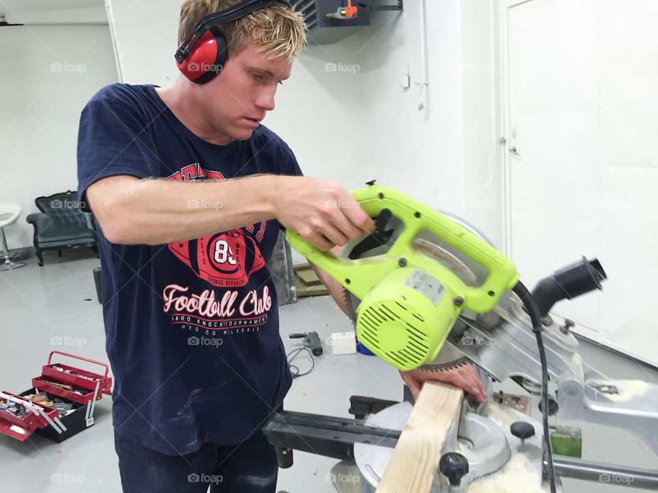 Man working with a cross-cut saw in a construction site.