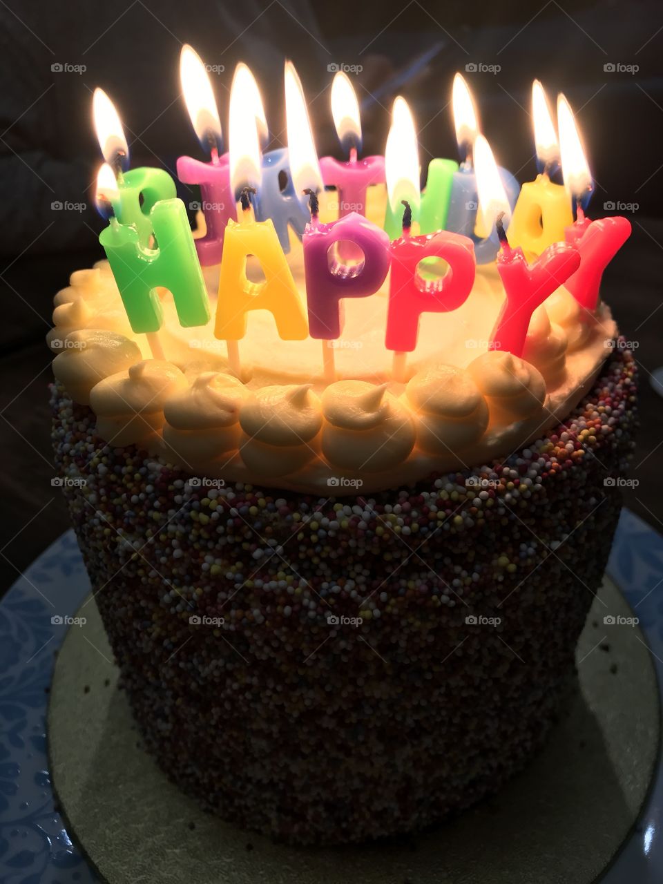 Happy Birthday Rainbow cake with candles alight