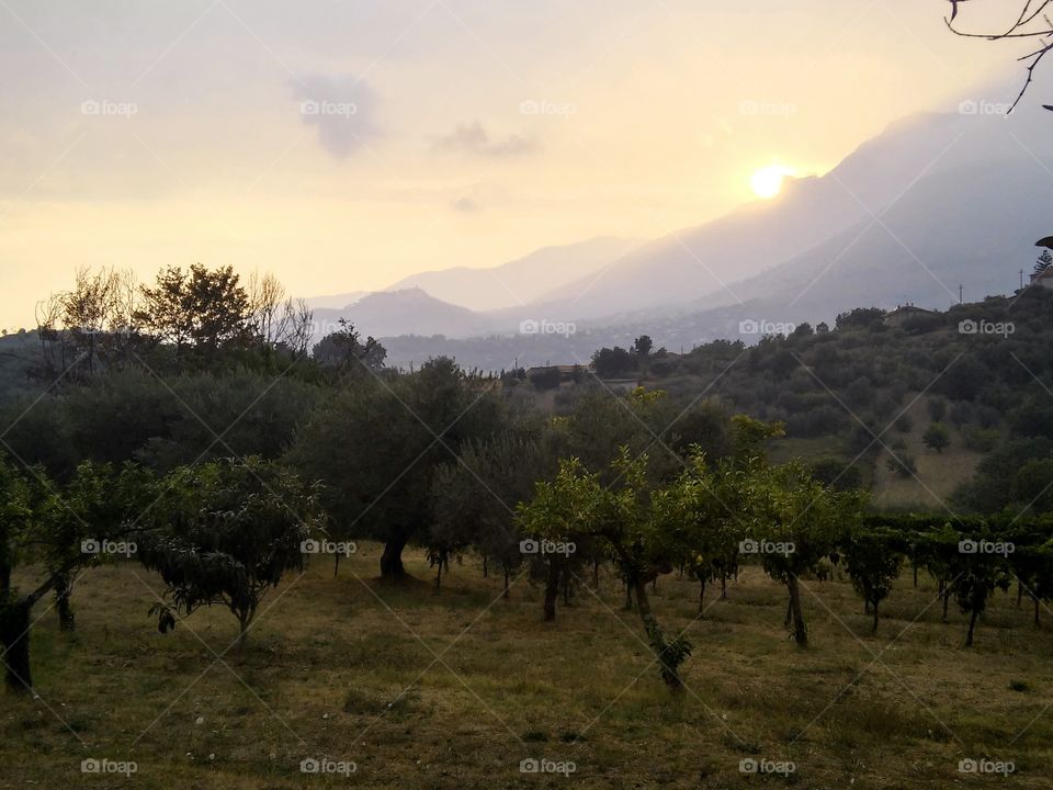 Sunset in valley. View on country while the sun hides beyond the mountains.