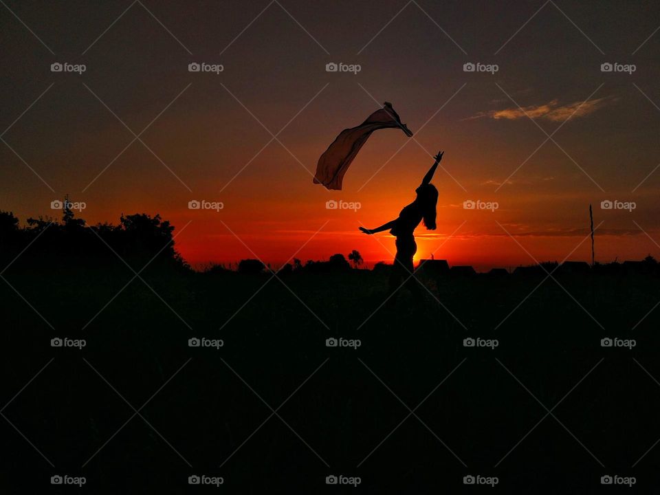 Girl playing with scarf. Silhouette on sky background