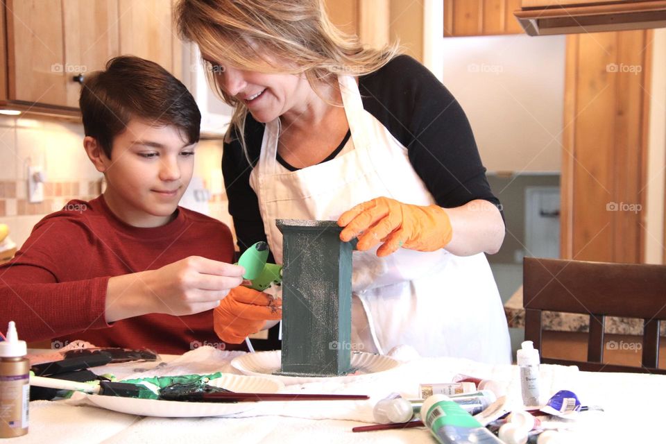 Mom and son painting and decorating bird house indoors 