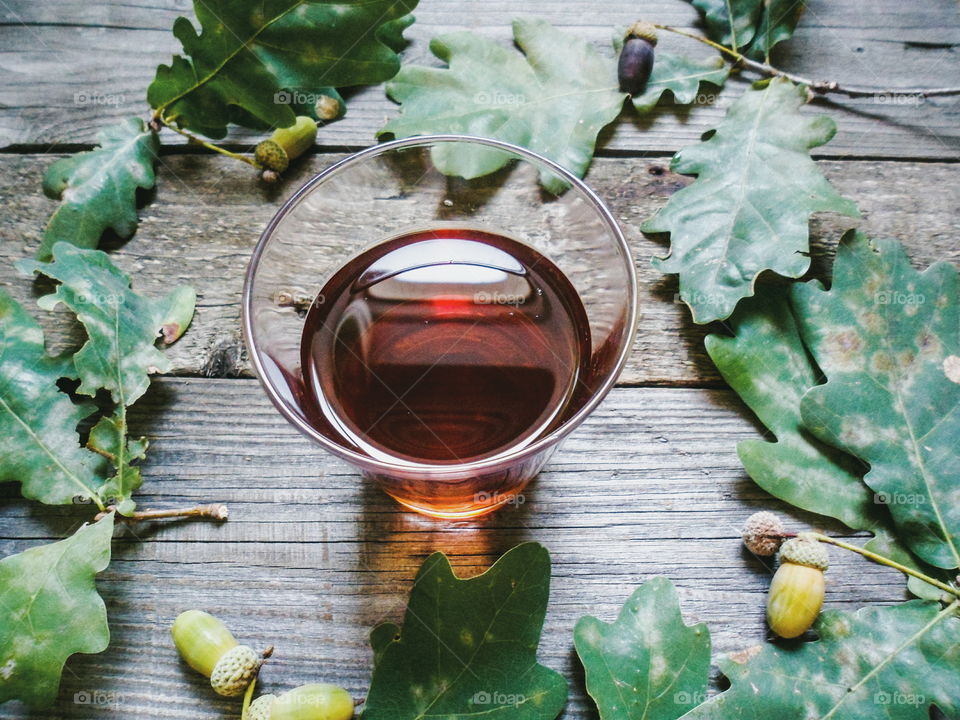 glass of whiskey and oak acorns on a wooden base