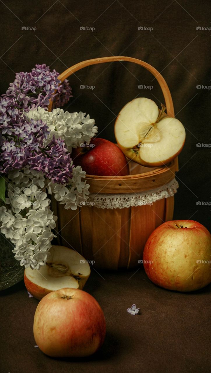 still life of apples and lilacs on a dark background