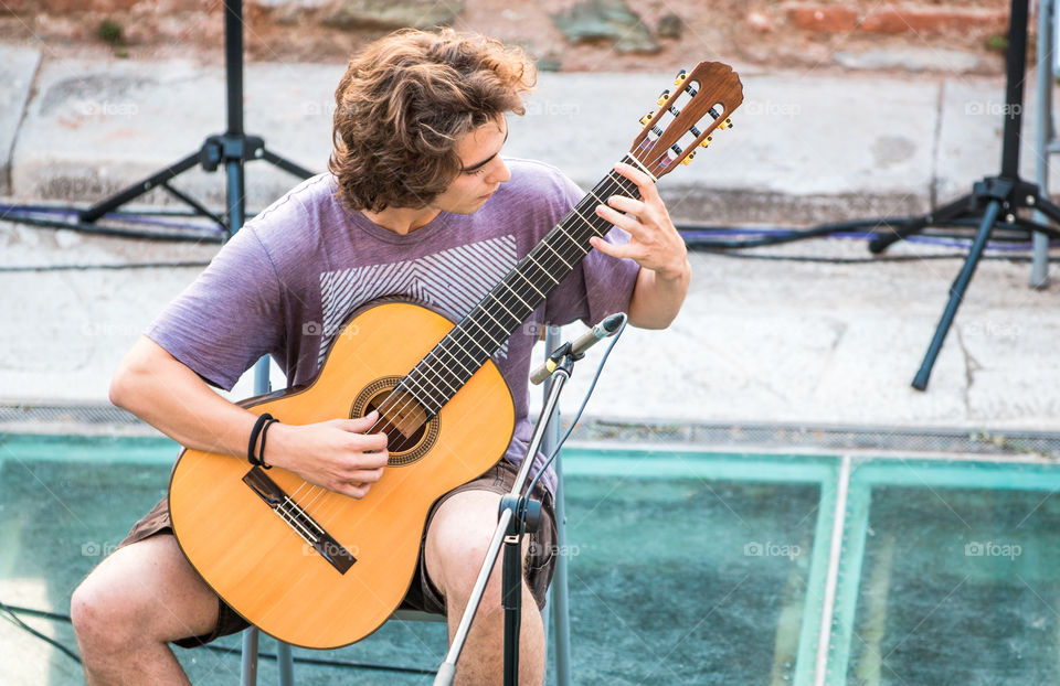 Young Man In Live Performance Playing Music On Classical Guitar
