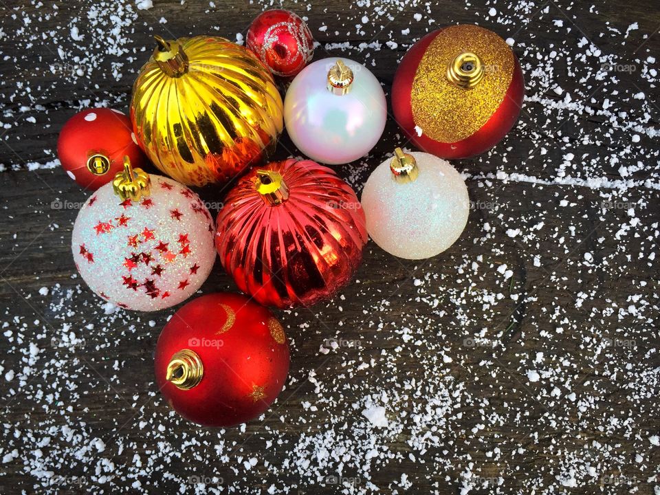 Red and white glittering Christmas globes on rustic wooden table powdered with snow