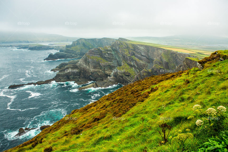 2019 memories of green grass and blue seas. Beautiful scenic landscape of rock cliffs and meadows on a rainy day.