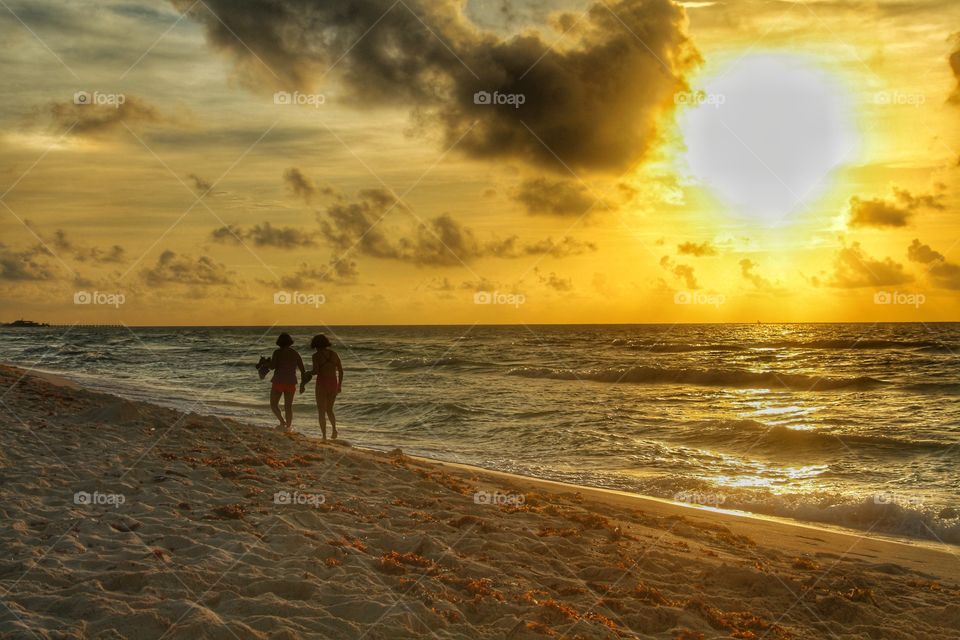 people walking in the beach at sunrise