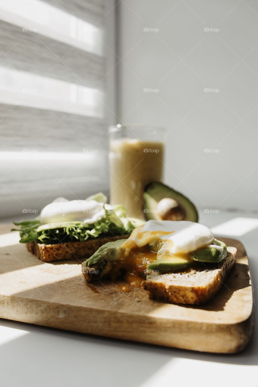 Healthy food - toasts with fresh green avocado end home eggs and smoothie made from banana and apple