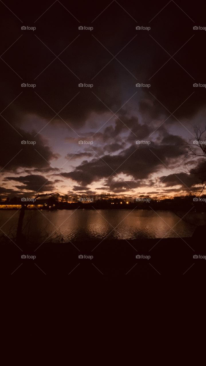 Evening sunset Reflective silhouette on Lake Water with Evening Colors timing for Sunset. Mostly Cloudy Heavy Clouds building for Strong Weather Front Headed to this Region. Twilight in effect.