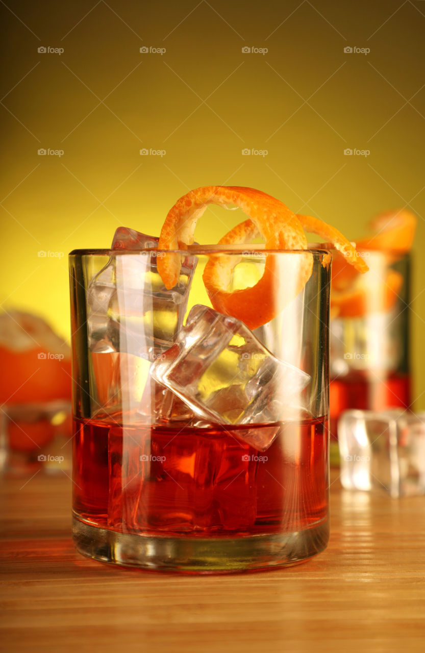 Alcoholic drink or juice with ice cubes and orange peel