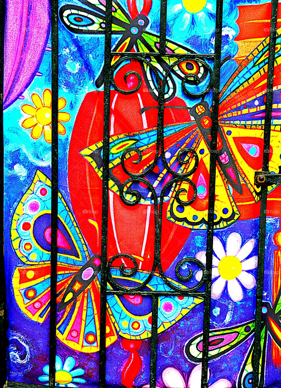 Clash of colors - Beautifully colored abstract butterflies on a door, behind a decorated iron door