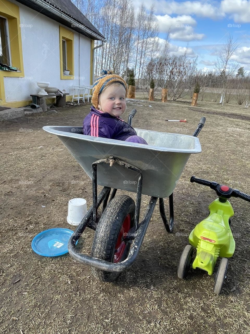 Little baby girl sitting in a wheelbarrow and smiling 