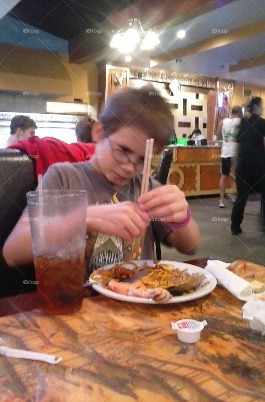 my son eating Chinese food..trying to use chopsticks...