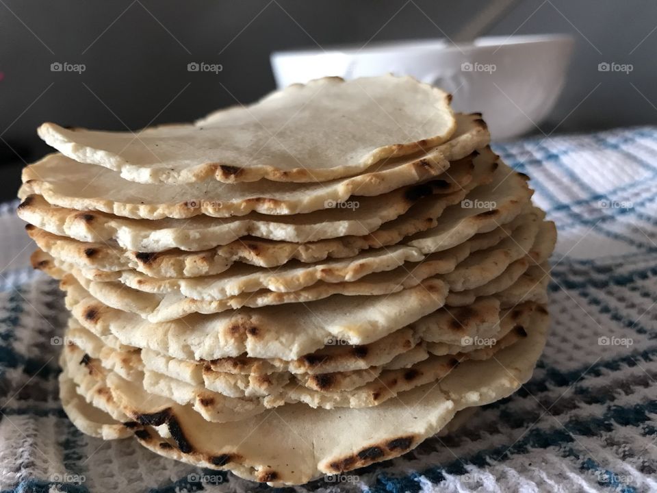 Pile of homemade tortillas in front of a bowl of soup