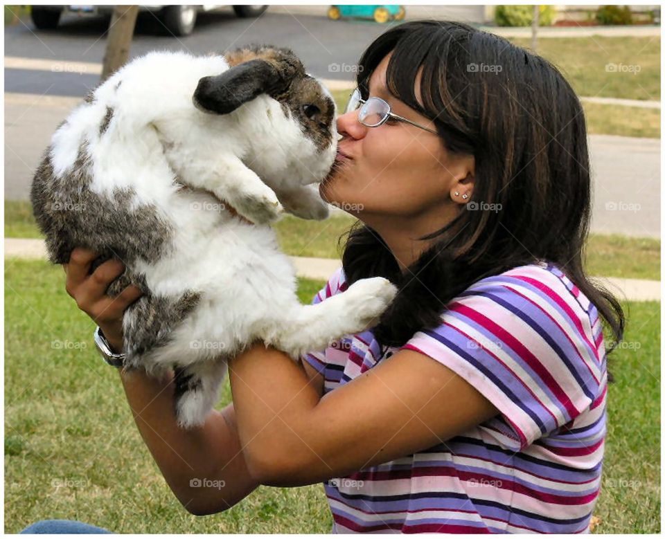 Young girl kissing her pet rabbit.