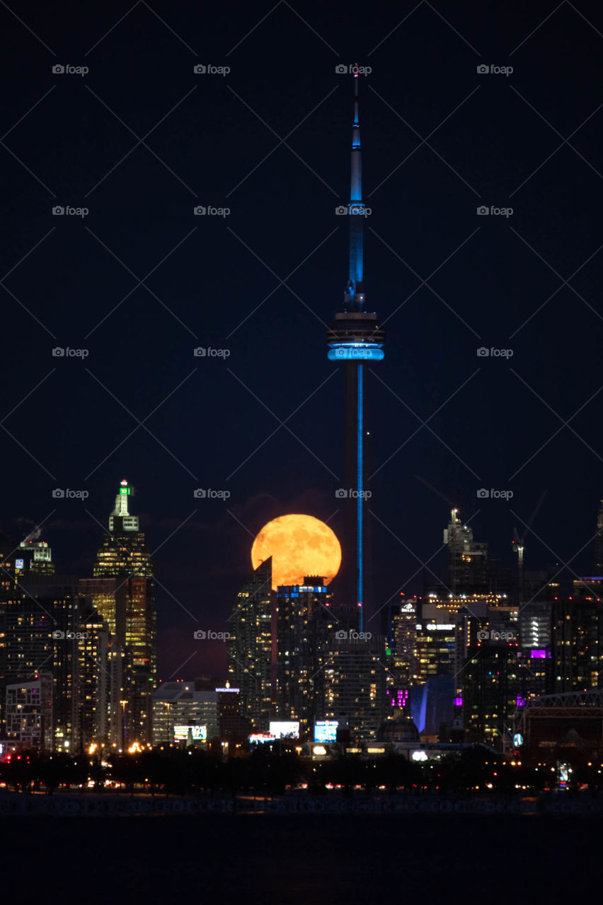 Full moon rising above the Toronto skyline, providing natural light on a beautiful clear night. 