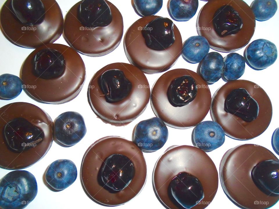 Round pieces of chocolate with blueberries on white background 