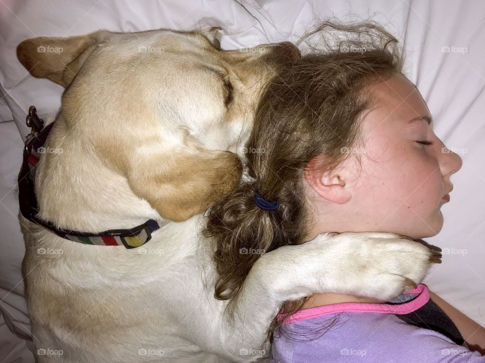 Girl and her big white dog resting their heads on a pillow
