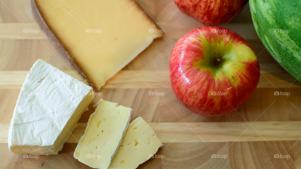 Healthy lifestyle and eating background with fresh fruit red apple and sliced cheese on wood platter 