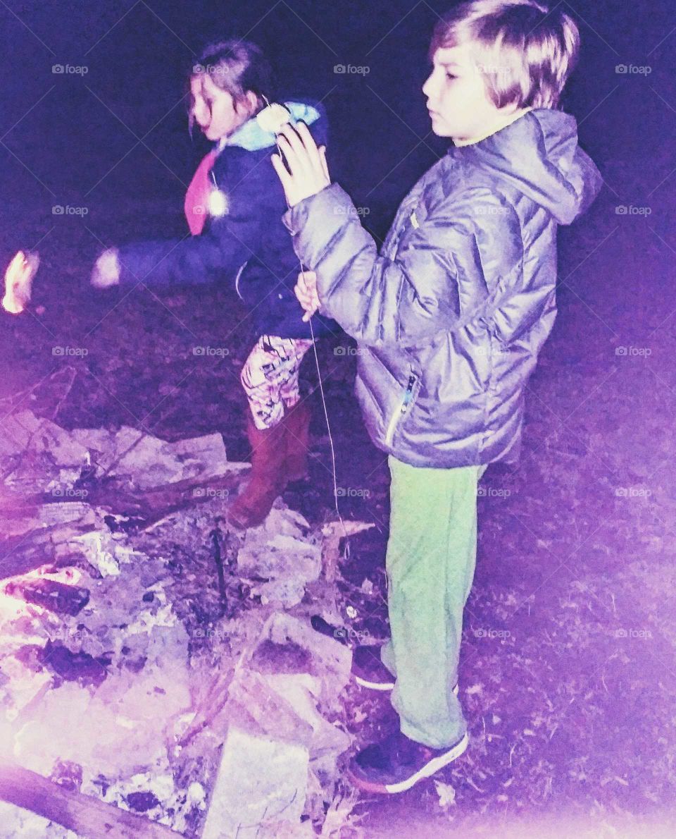 Young boy and girl roasting marshmallows on a fire on a fall evening.