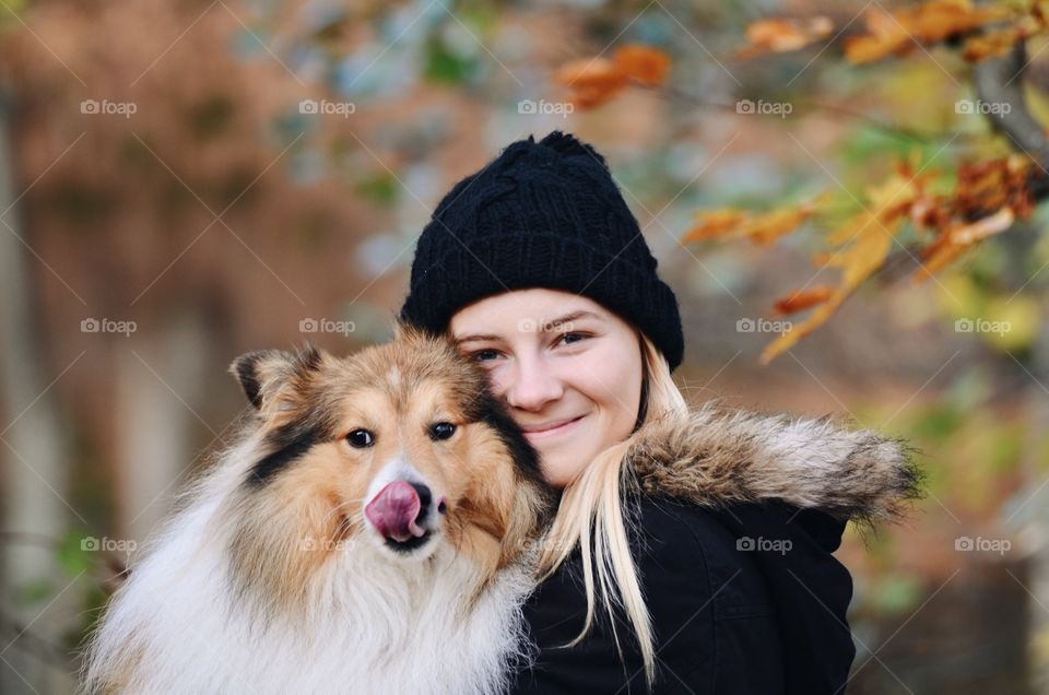 Portrait of a young woman or girl with a Sheltie Shetland Sheepdog dog outdoors in autumn