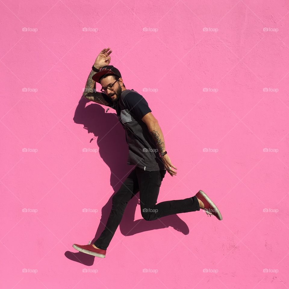 Jumping for joy on a pink wall. 