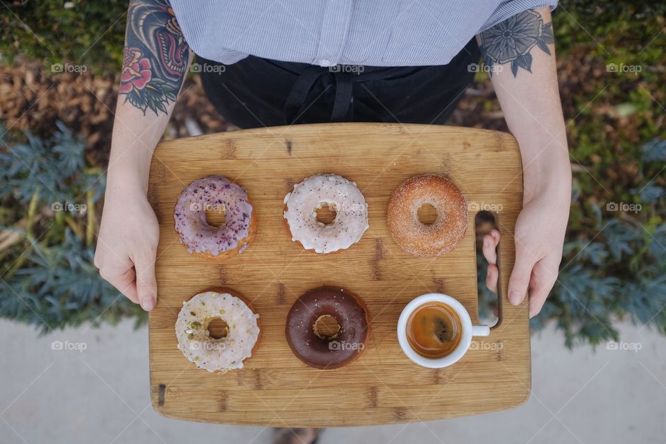 Woman holding a tray with doughnuts. 
