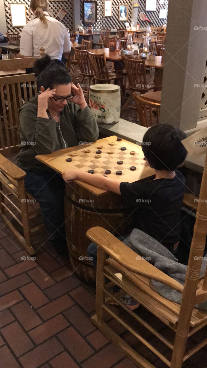 Boy and mom playing checkers in a Cracker Barrel