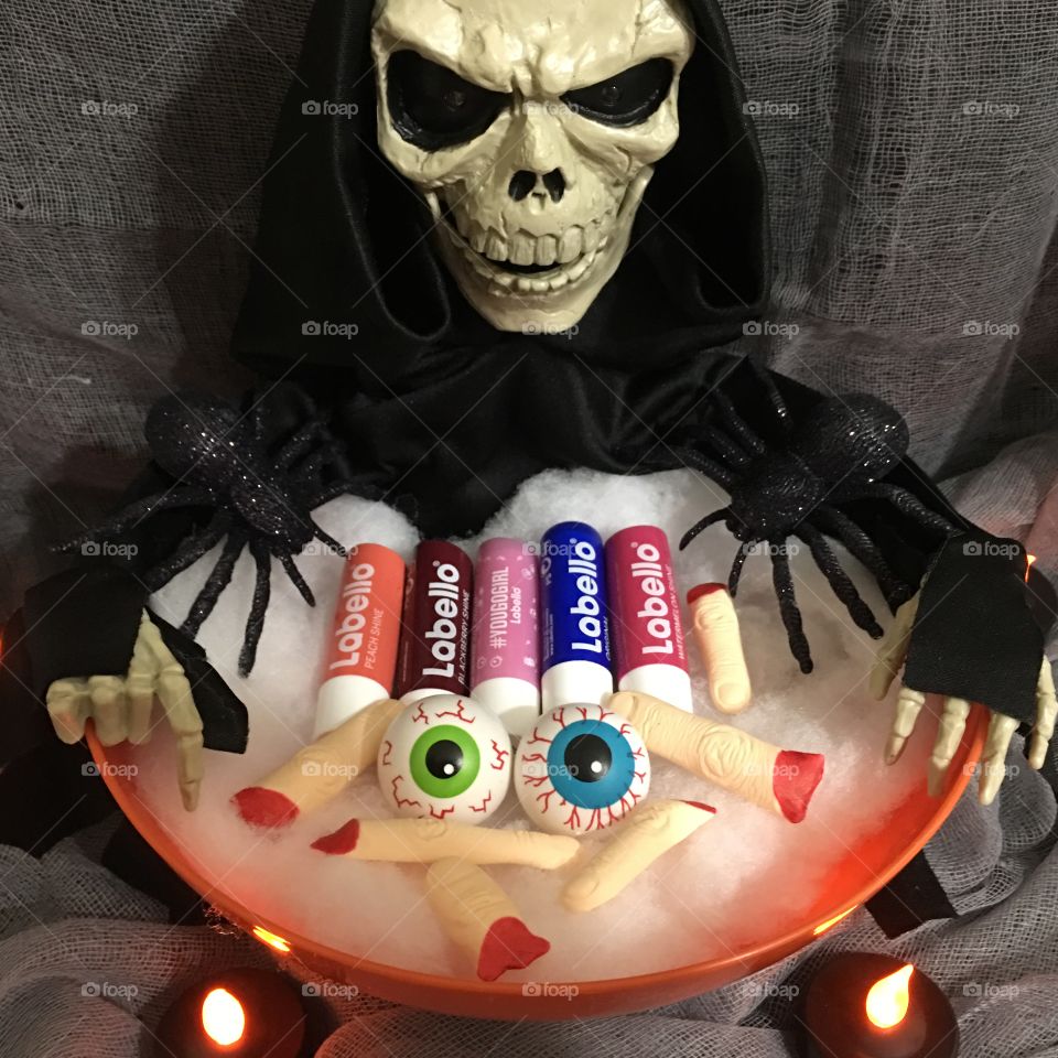Scary skull with bunch of edible fingers, toy eyeballs and Labello lip balms and spiders